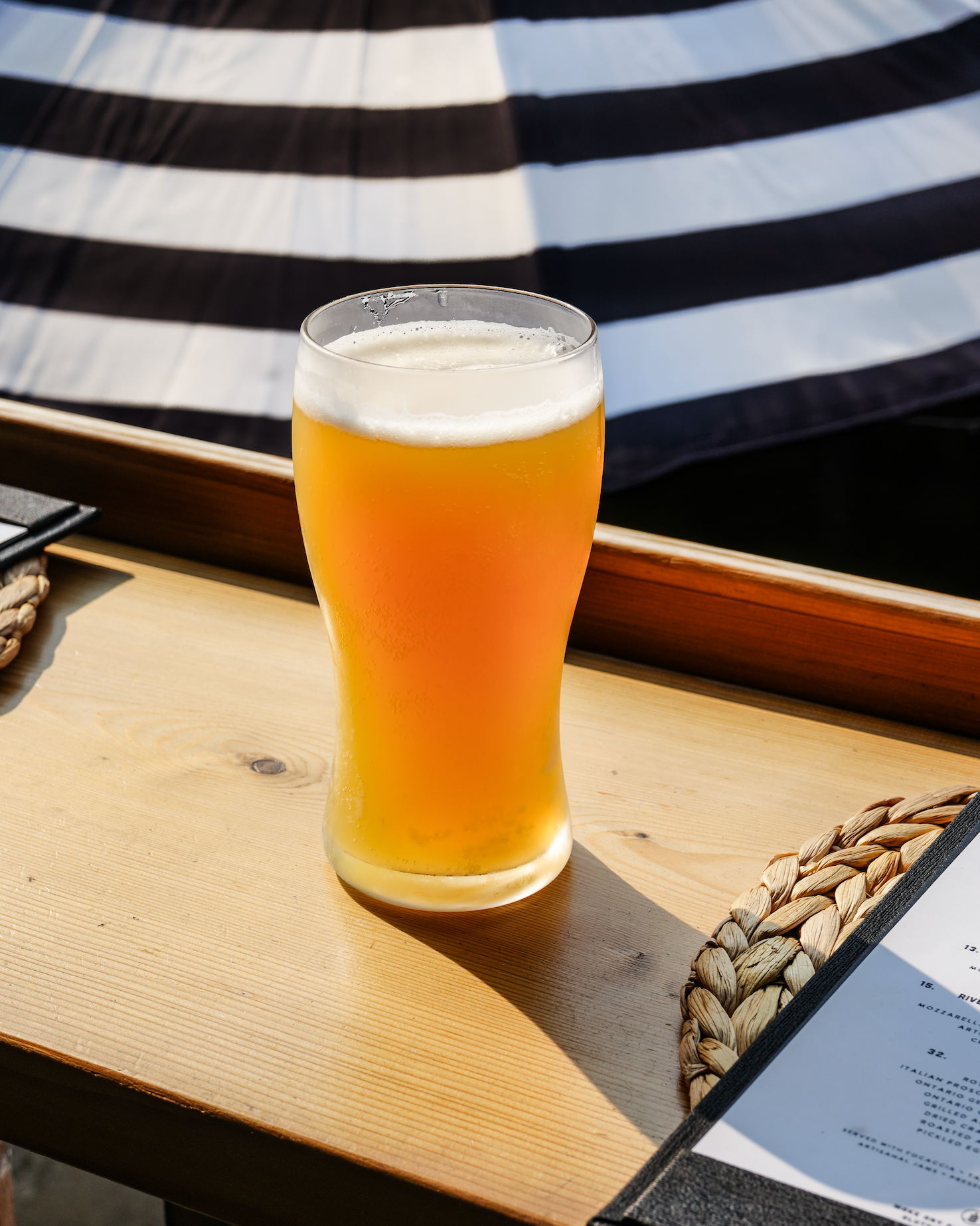 Glass of beer on a wooden table with a striped fabric in the background