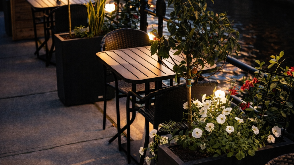Outdoor patio with tables, chairs, and striped umbrellas at night.