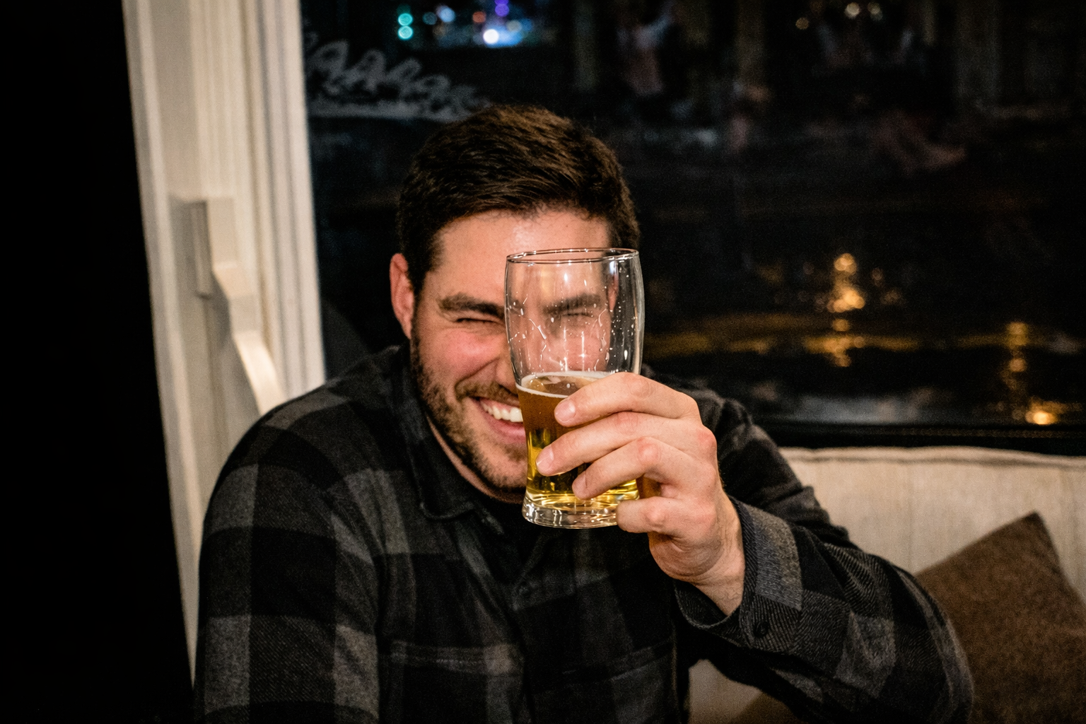 Man holding a glass of beer in a dimly lit room